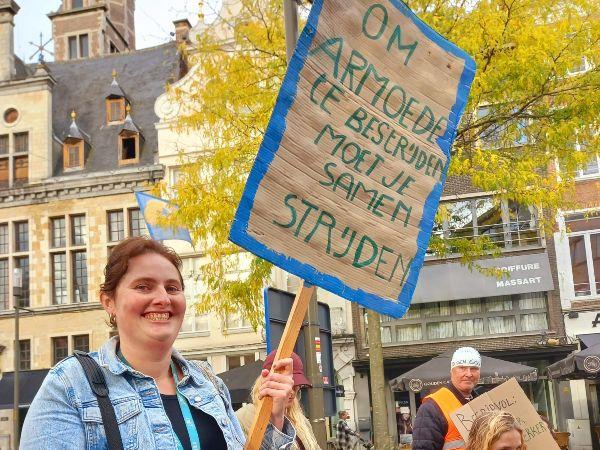 betoogster met bord 'om armoede te bestrijden moet je samen strijden'